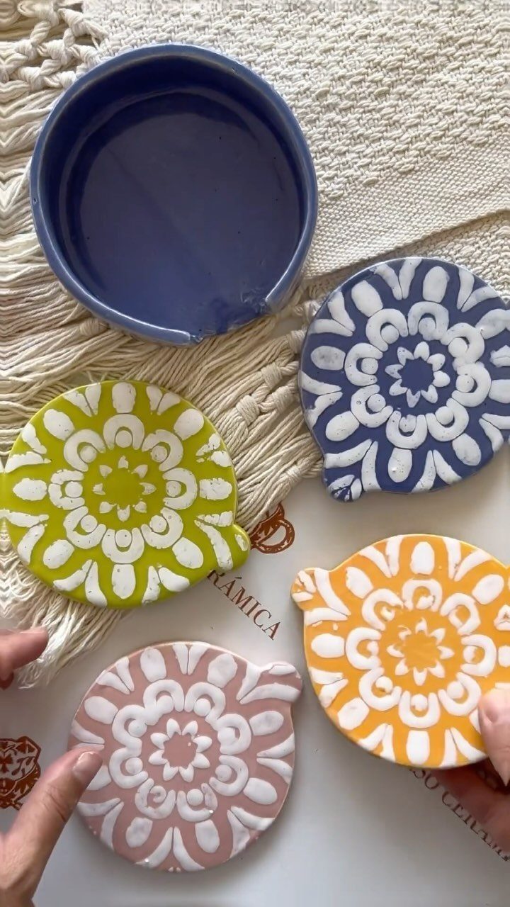 Handcrafted ceramic coasters with colorful floral patterns and a small blue bowl.
