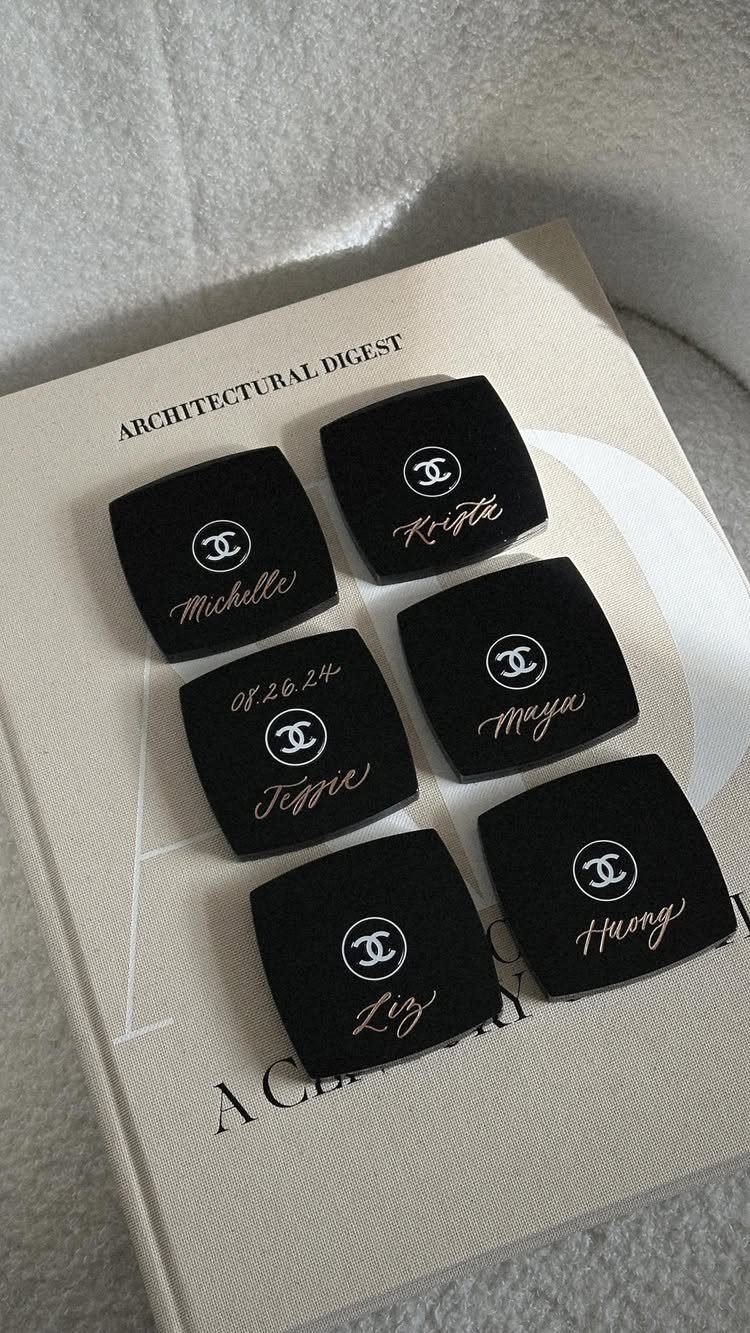 Black velvet jewelry boxes with gold names and logos on a white book