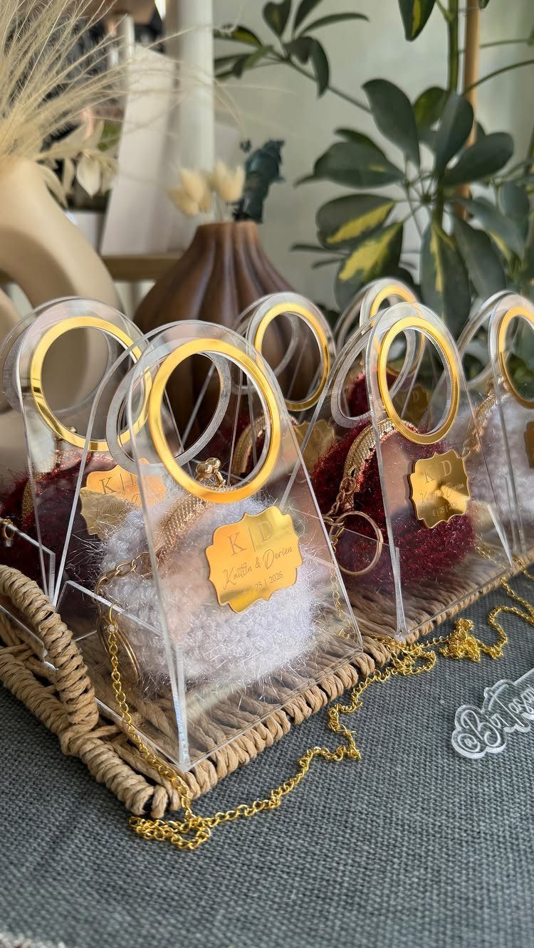 Acrylic keychains with gold handles and personalized tags on a woven tray