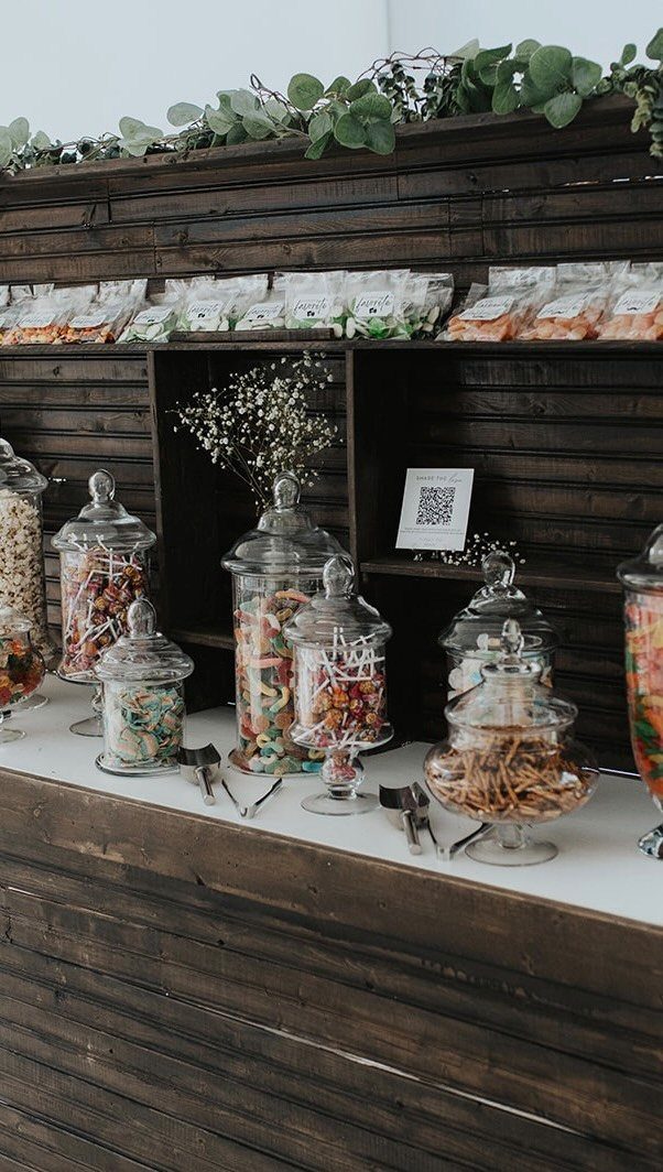 Candy buffet with glass jars of colorful sweets on a rustic wooden bar