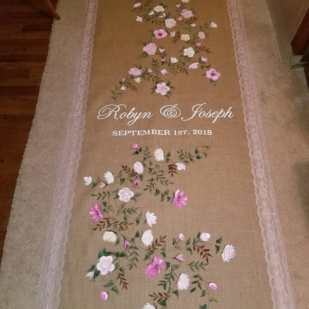Burlap aisle runner with pink floral designs and personalized wedding names and date.