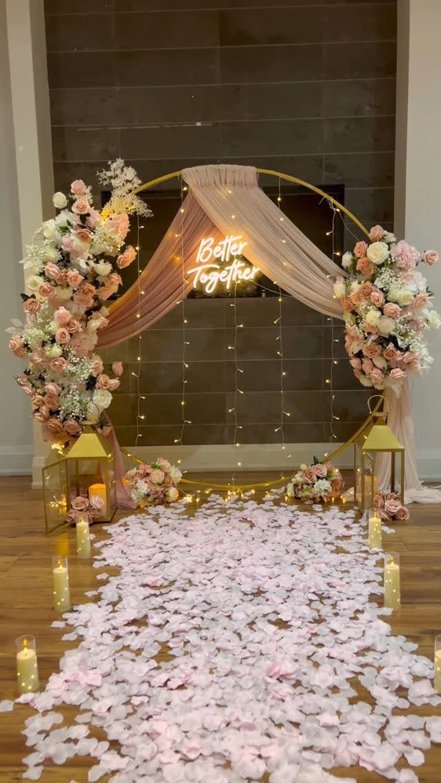 Pink flower petals covering a wedding aisle leading to a floral circular arch.
