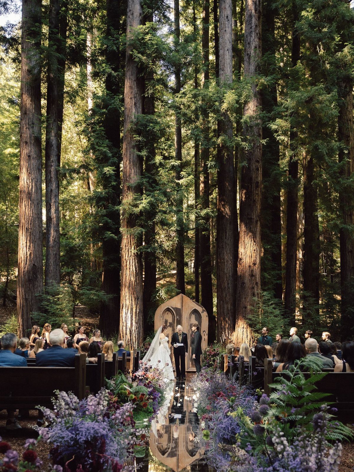 Wedding couple standing before a vintage door altar in a redwood forest setting.
