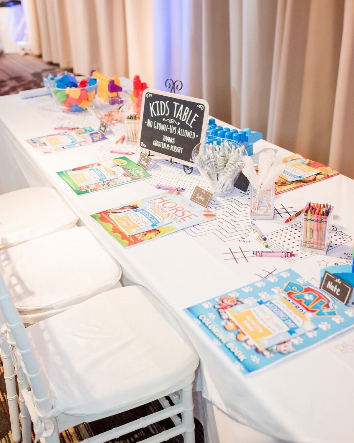 Children's wedding table with coloring books, crayons, and a kids table sign.