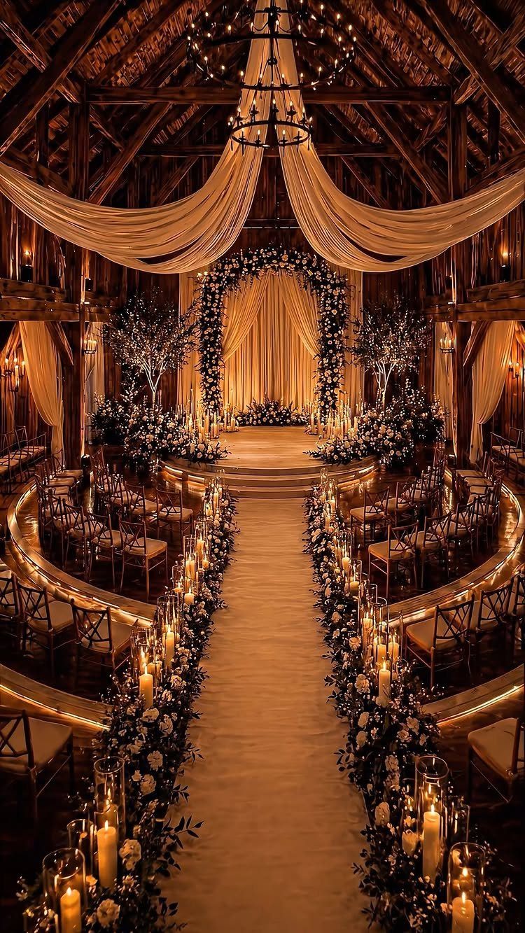 Curved wedding ceremony seating with wooden chairs, floral aisle, and rustic barn backdrop.
