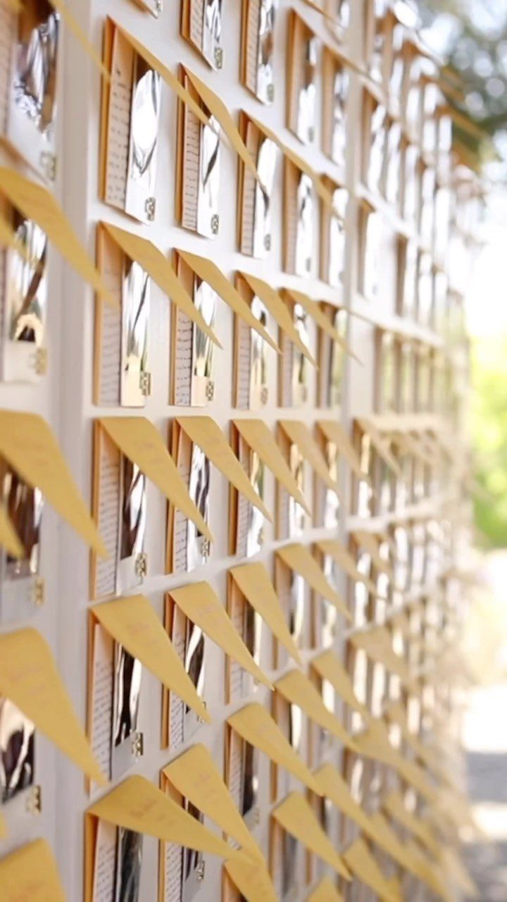 Yellow escort cards and envelopes arranged in a grid on a white wall.