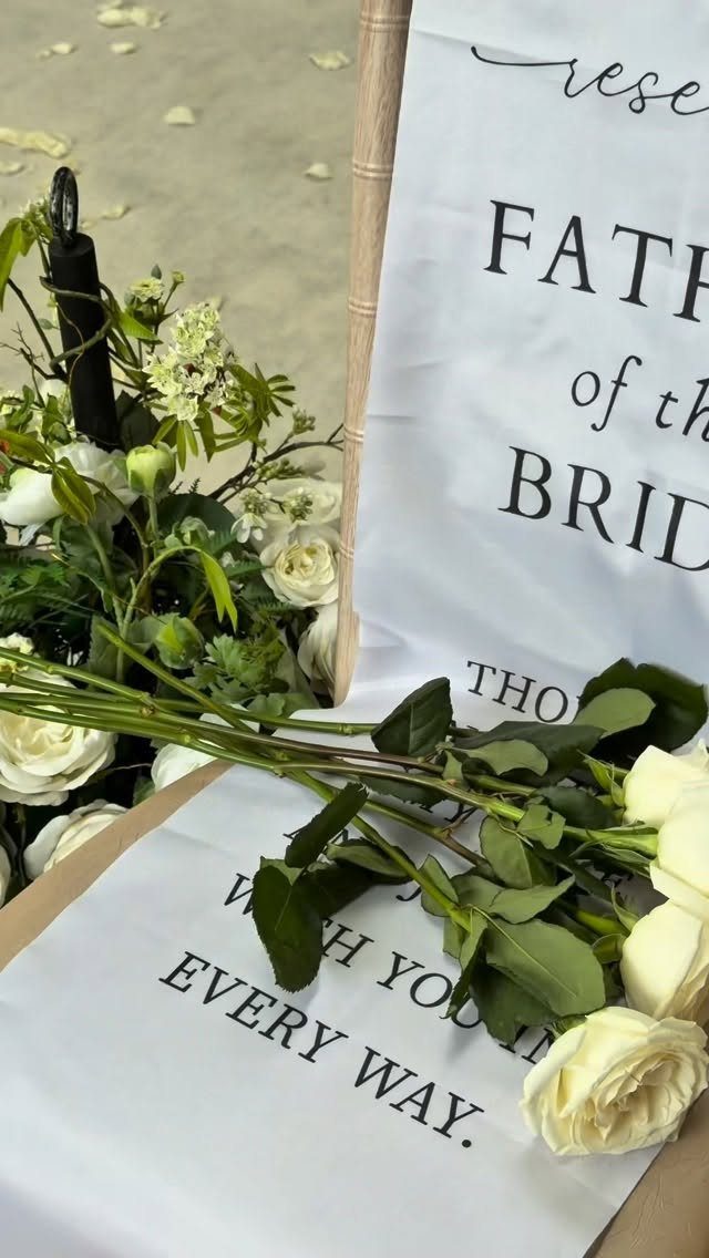 Reserved sign for Father of the Bride with white roses on a beach.