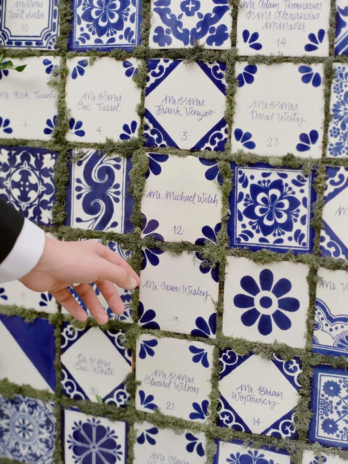 Blue and white patterned ceramic tiles with names used as a wedding seating chart.