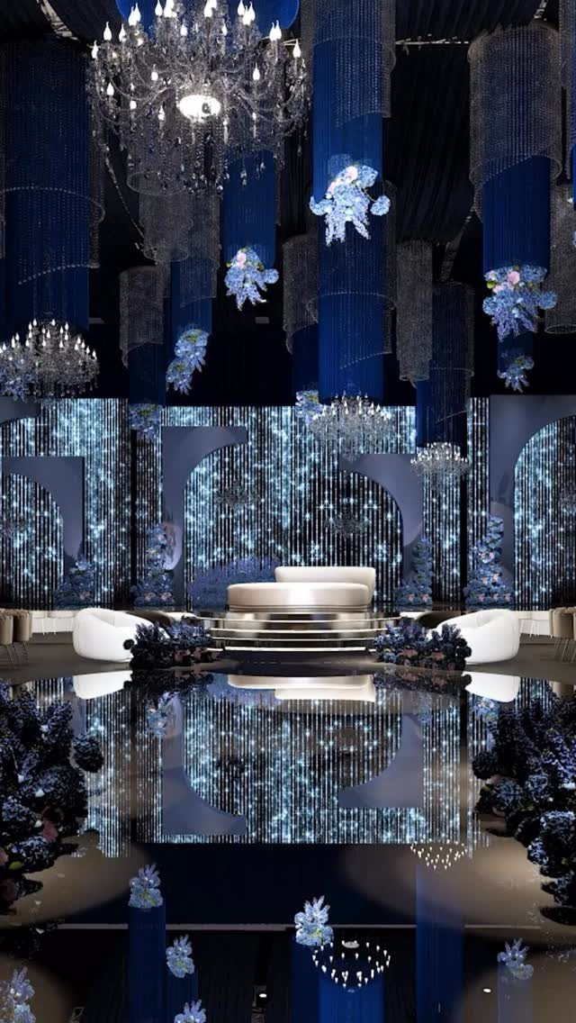Opulent event space with deep blue drapes, crystal chandeliers, and white curved furniture.
