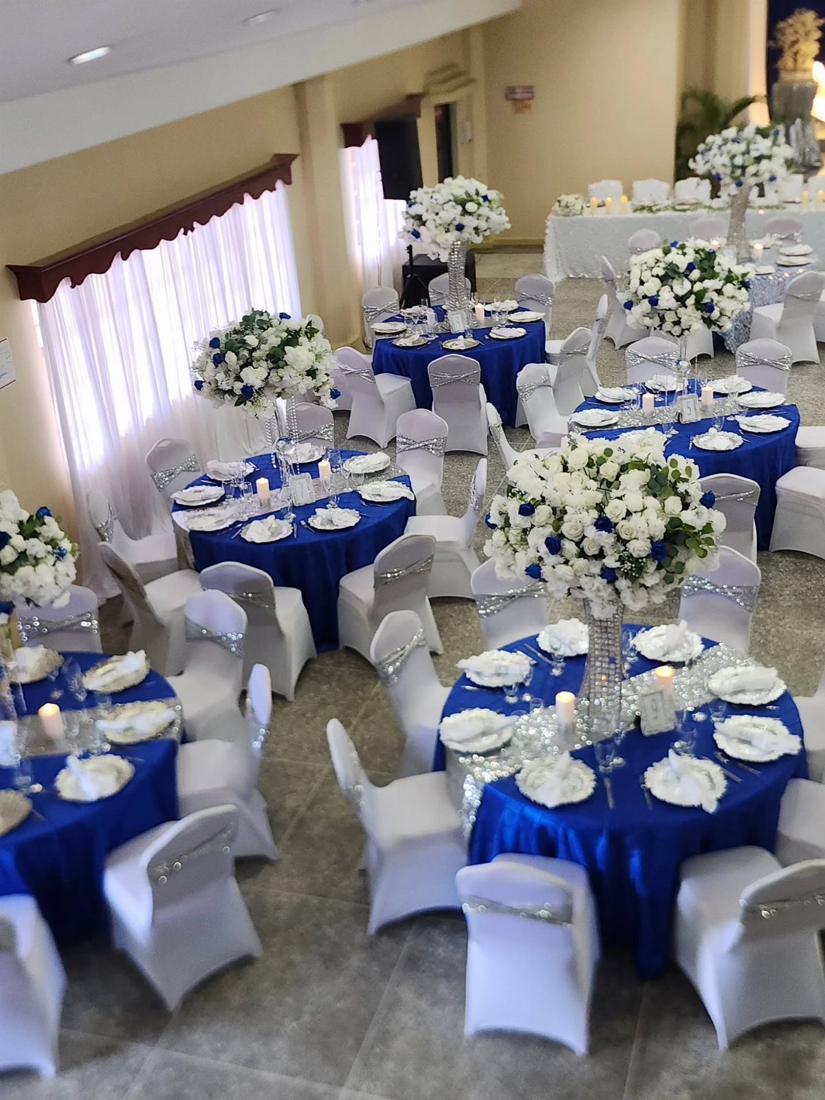 Royal blue tablecloths and white floral centerpieces in a wedding reception hall.