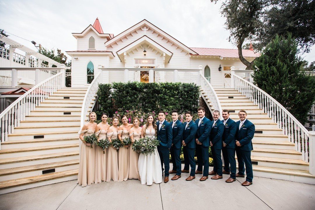 Wedding party with bridesmaids in champagne dresses and groomsmen in navy blue suits.