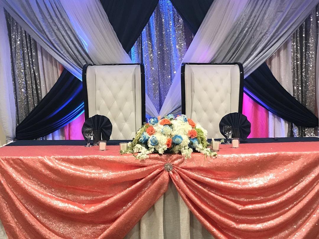 Coral sequined wedding table with navy blue runner and white floral centerpiece