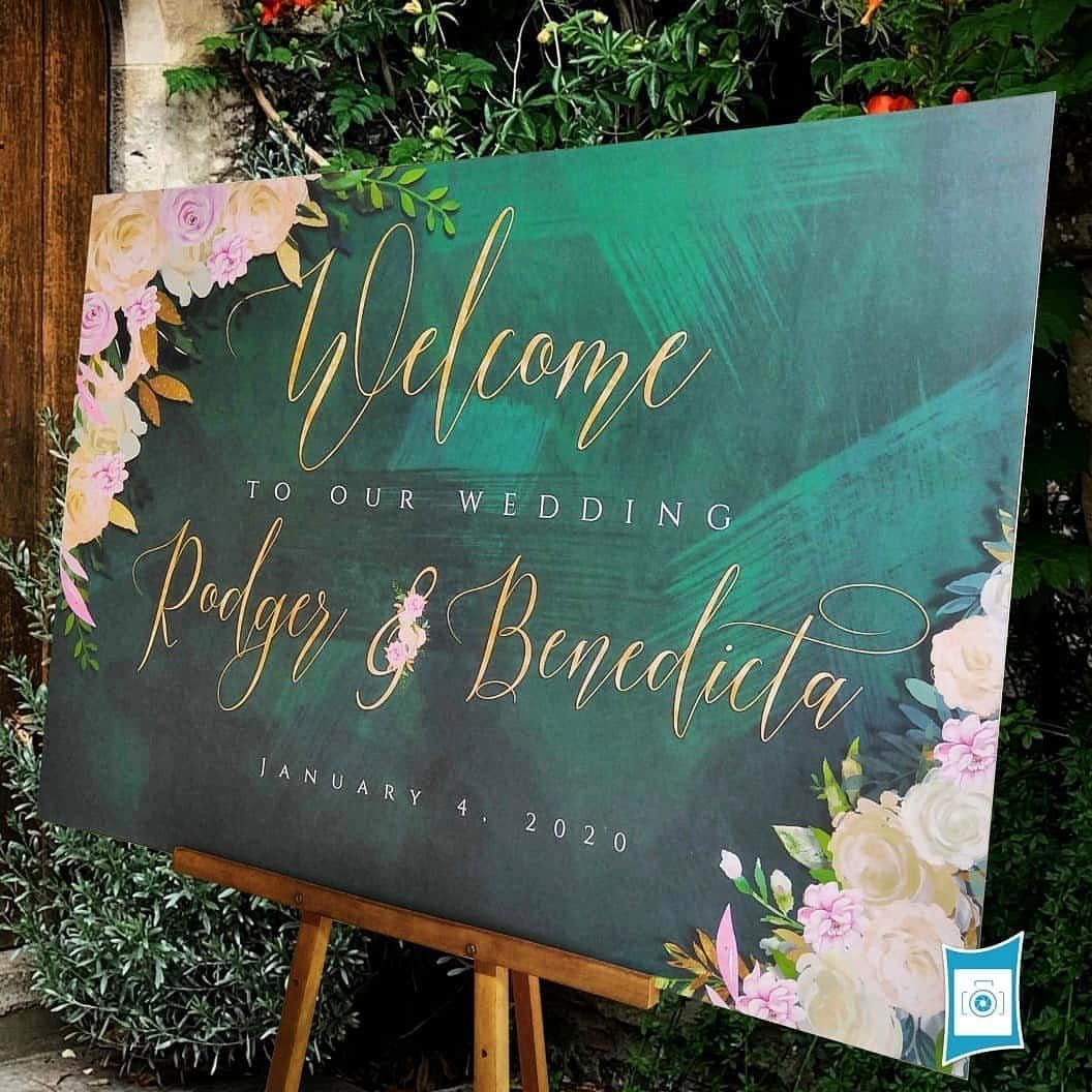 Emerald green wedding welcome sign with gold lettering and blush pink floral accents.