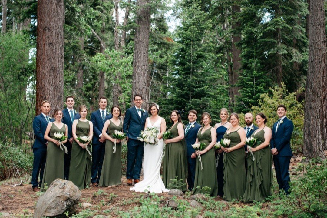 Wedding party in a forest with olive green dresses and navy blue suits.