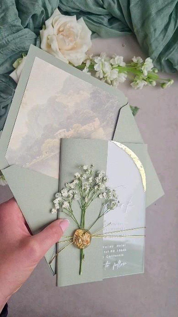 Sage green wedding invitation with white baby's breath and gold foil accents.