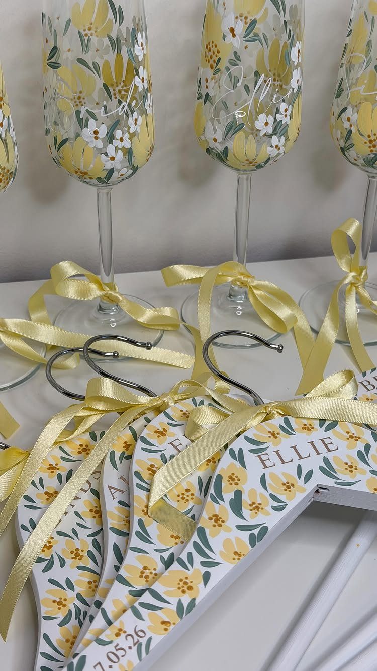 Hand-painted champagne glasses with yellow flowers and matching personalized floral clothing hangers.