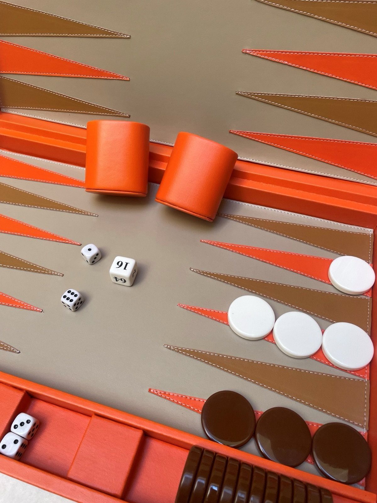 Luxury leather backgammon set with orange and brown accents and white game pieces.