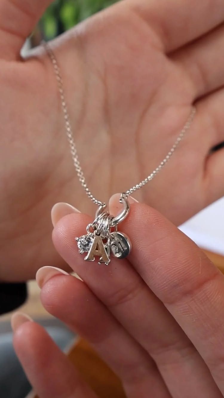 Silver chain necklace with a letter A charm and crystal held in hand