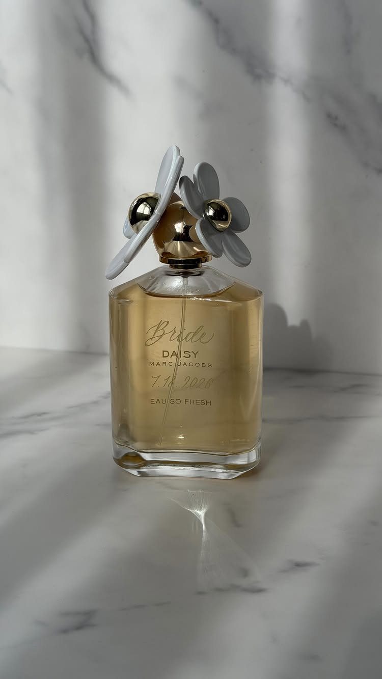 Perfume bottle with daisy cap and Bride lettering on a marble surface