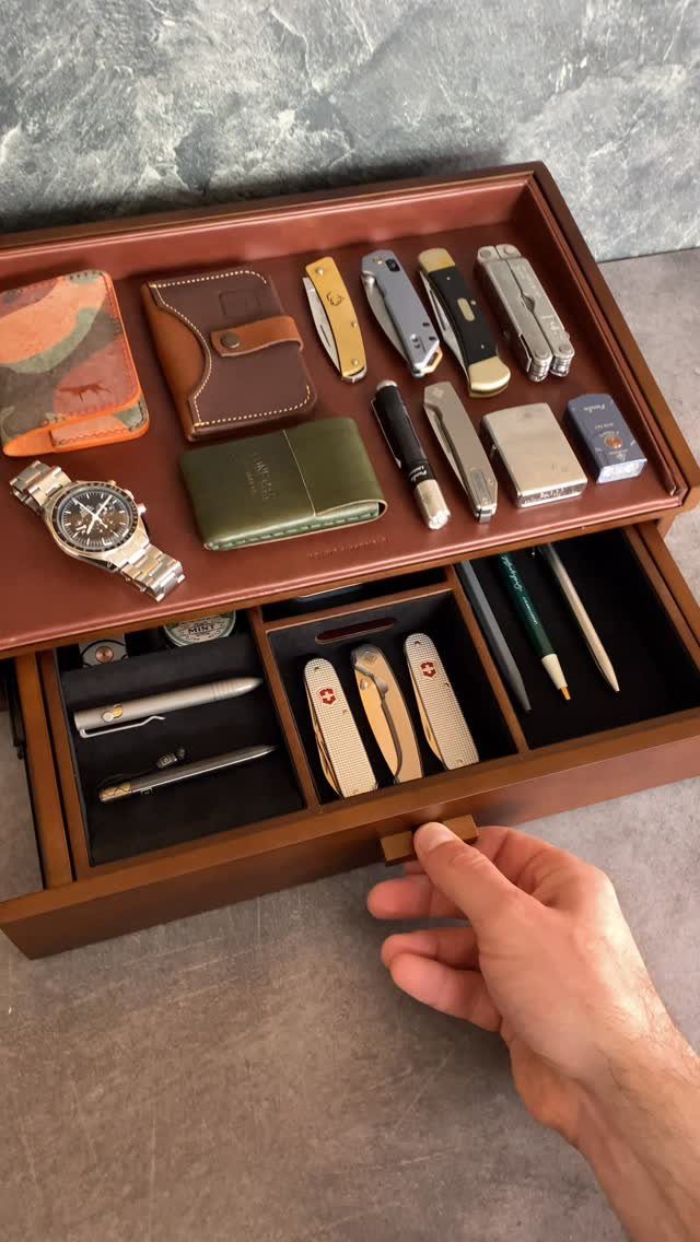 Wooden valet tray with a watch, wallets, and pocket knives as a gift.