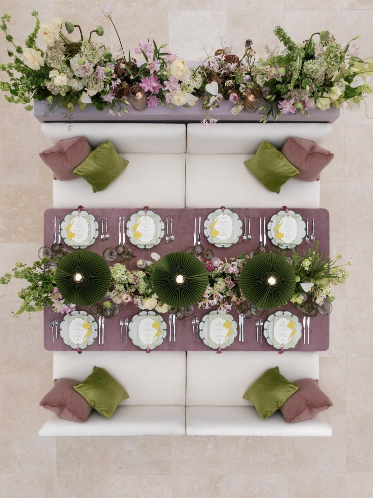 Wedding head table with purple runner, white benches, and green floral centerpieces.