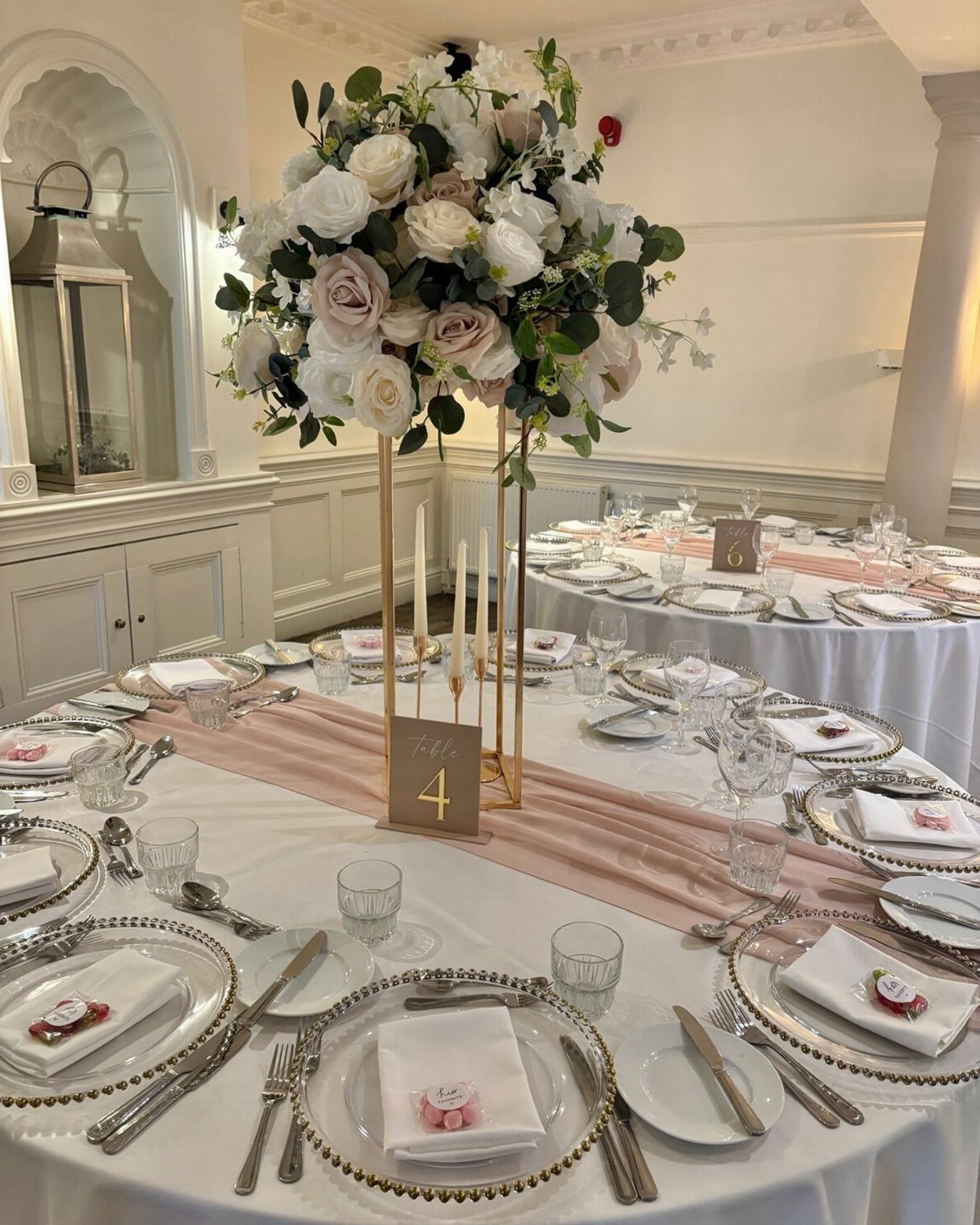 Tall floral centerpiece with white and blush roses on a wedding table