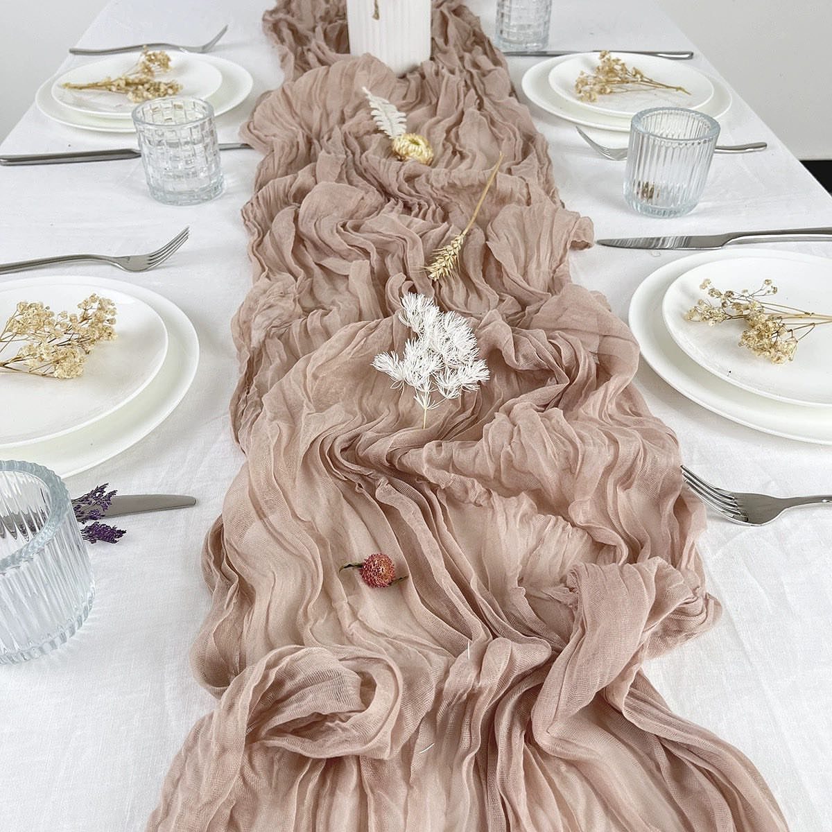 Beige ruffled fabric table runner on a white wedding table with elegant place settings