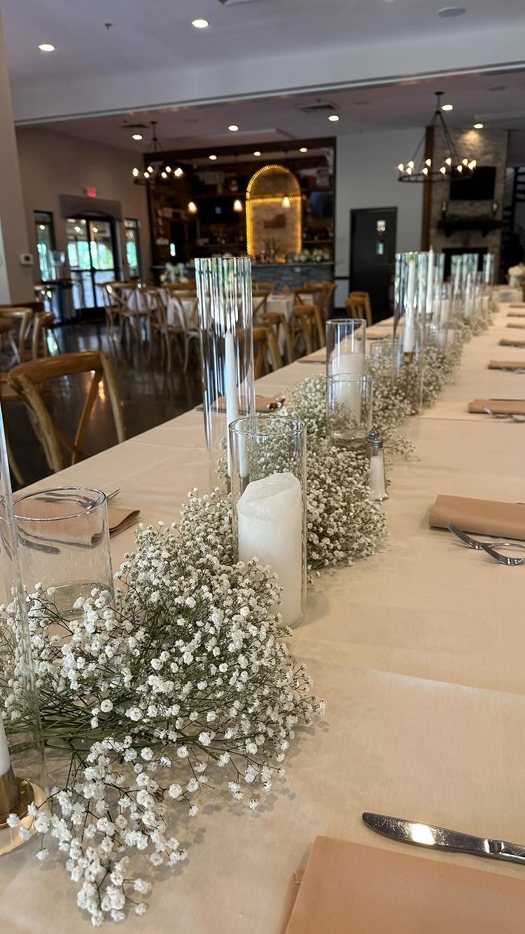 Long wedding head table with baby's breath floral runner and white cylinder candles.