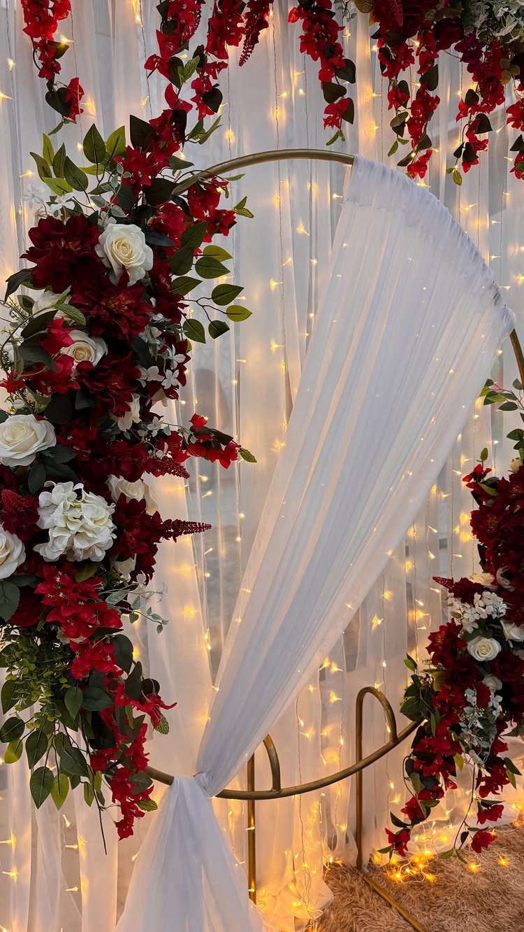 Gold circular wedding arch with red and white roses and warm fairy lights