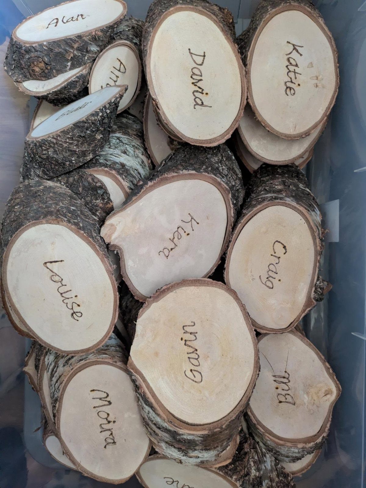 Engraved wooden log slices with names used as rustic wedding place cards.
