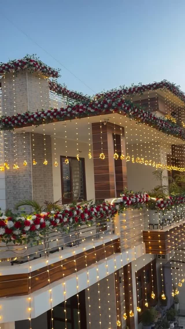 House exterior decorated with red and white flower garlands and hanging fairy lights.