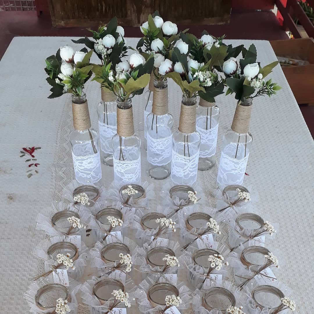 Glass milk bottles with lace and twine holding white roses on a table