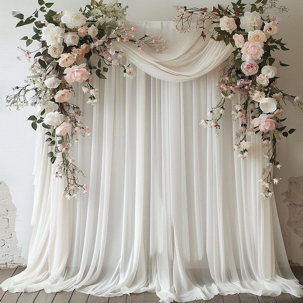White sheer fabric backdrop decorated with pink and white roses for a wedding.