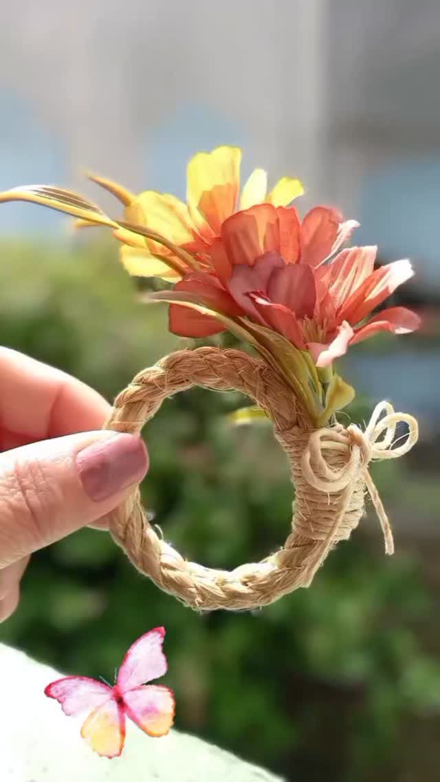 Twine-wrapped napkin ring decorated with orange and yellow artificial flowers and a bow.