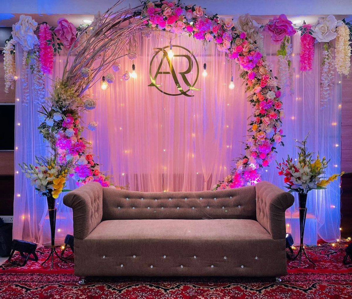 Gold initials A and R hanging inside a circular floral wedding arch backdrop