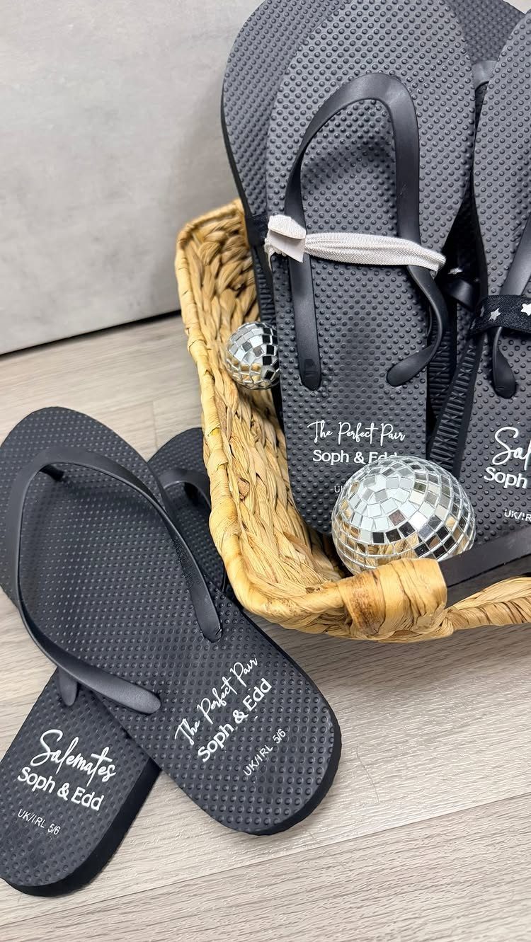 Black personalized wedding flip-flops in a wicker basket with small disco balls.