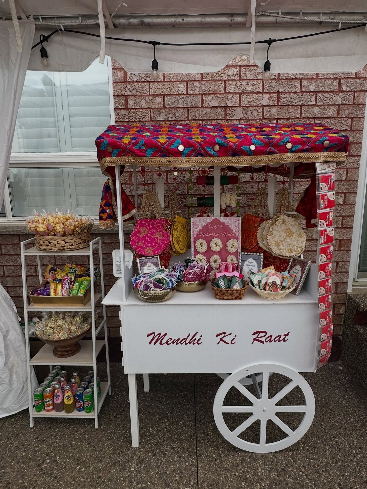 White wooden favor cart with colorful canopy displaying gift baskets and treats
