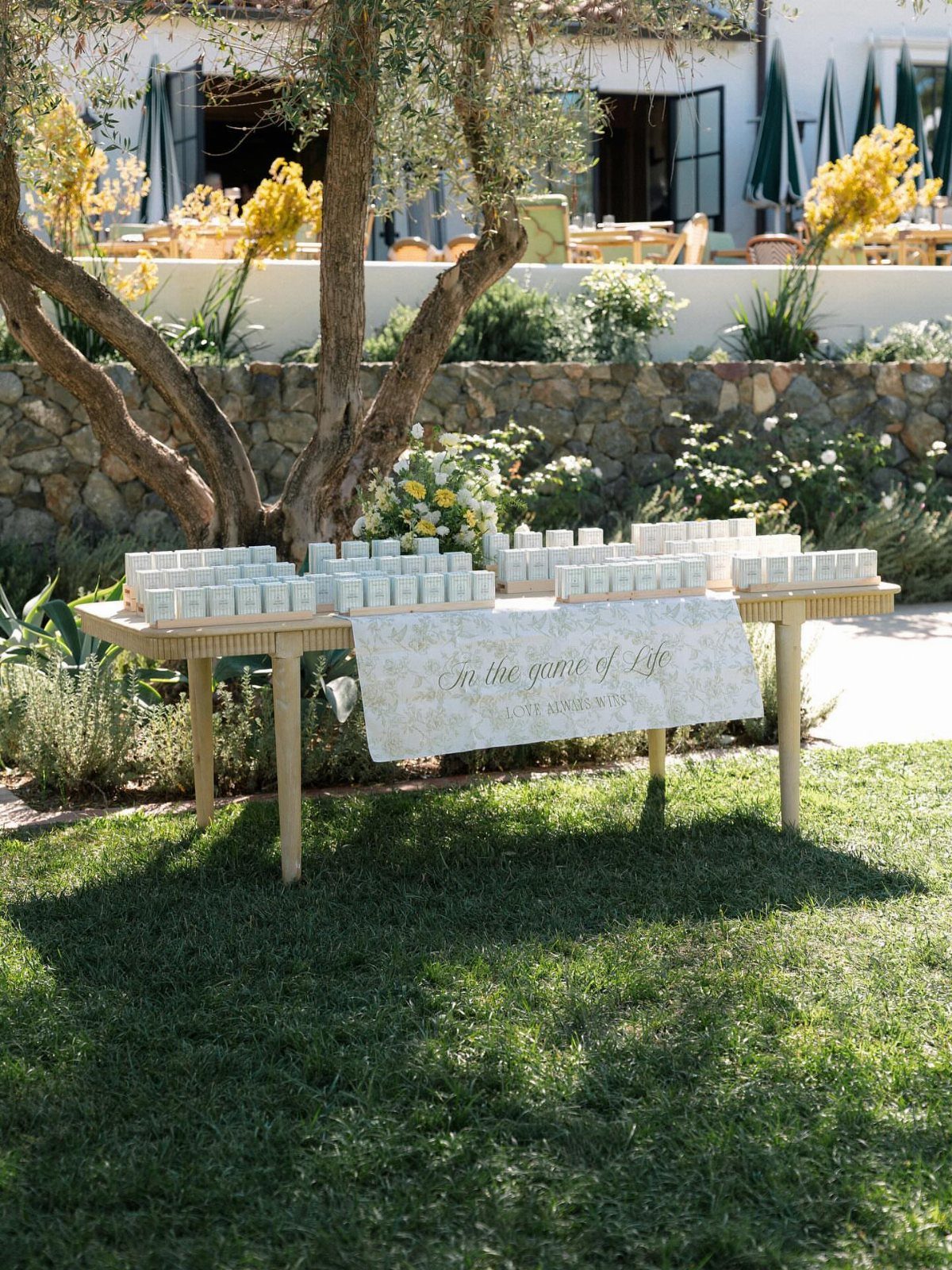 Rows of small white favor jars on a wooden table outdoors with banner