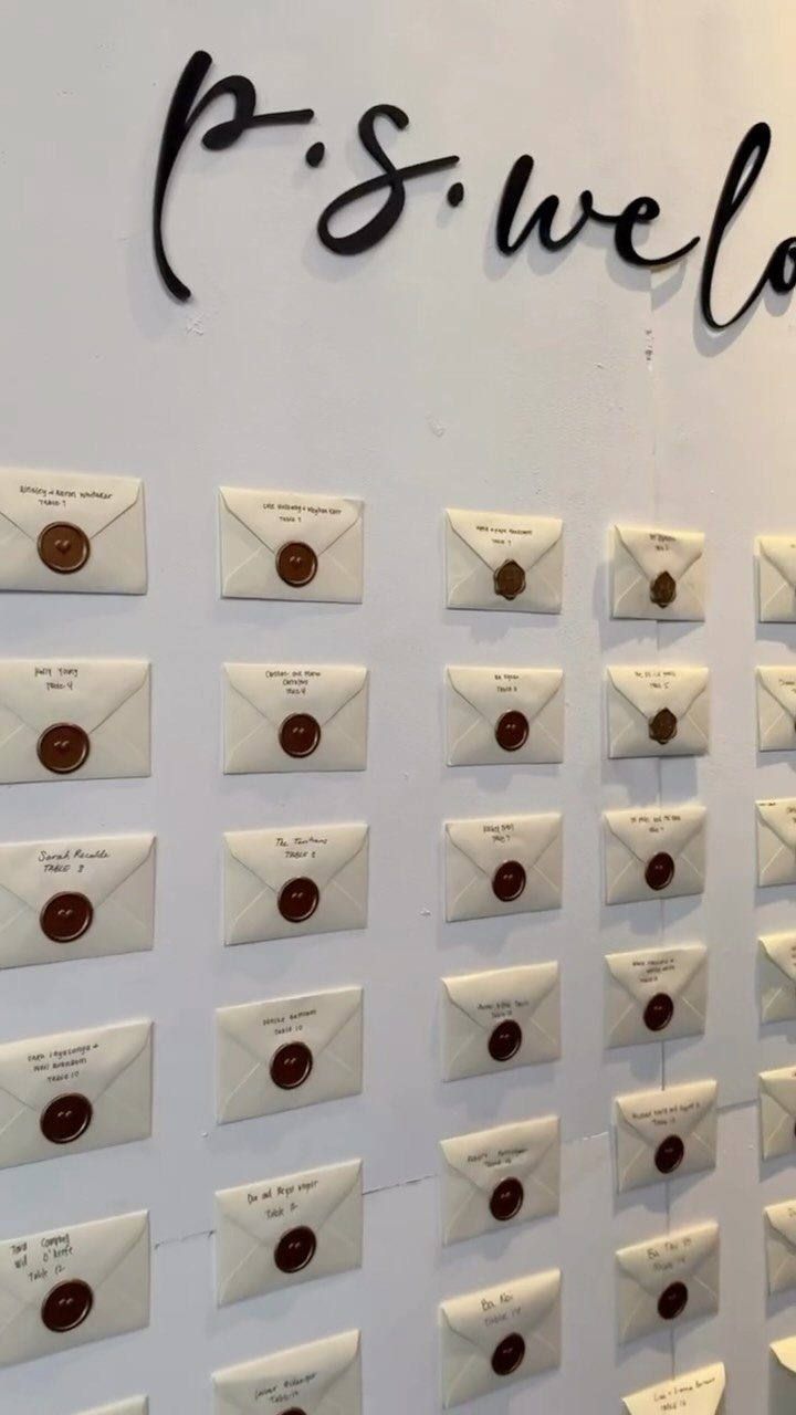 White envelopes with brown wax seals arranged in a grid on a white wall