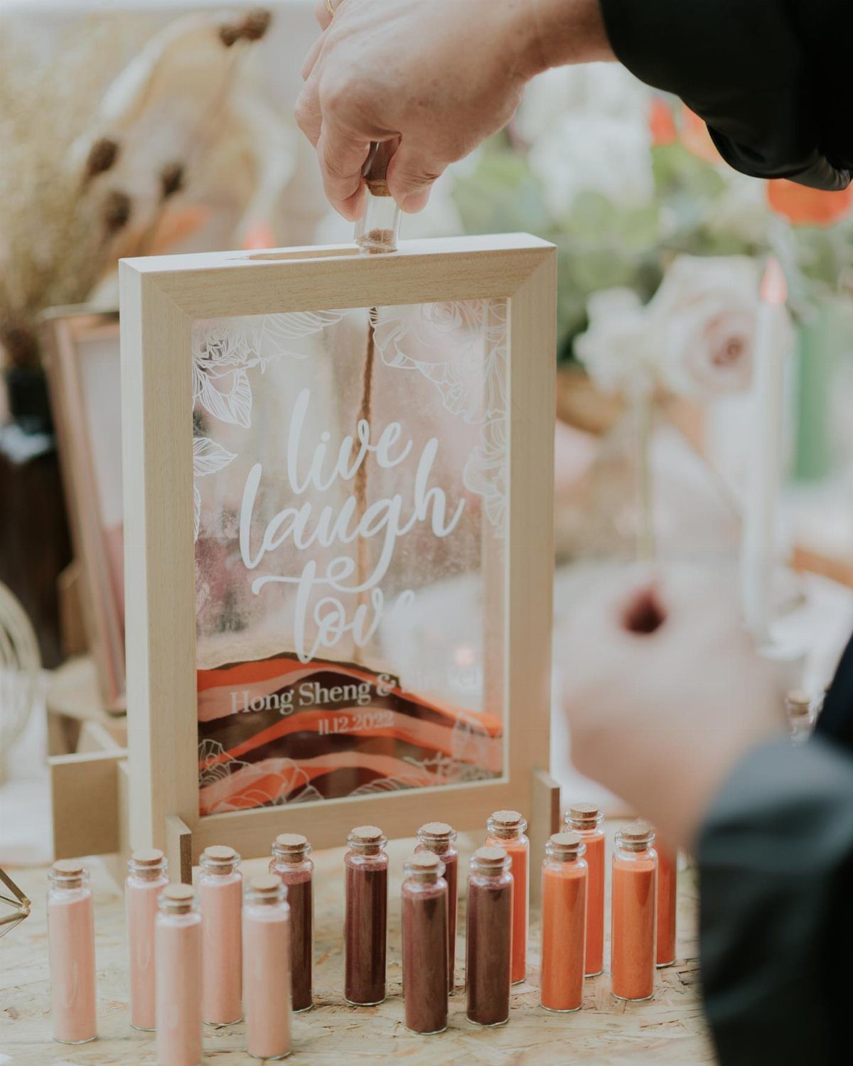 Hand placing a small glass vial into a wooden frame favor display box