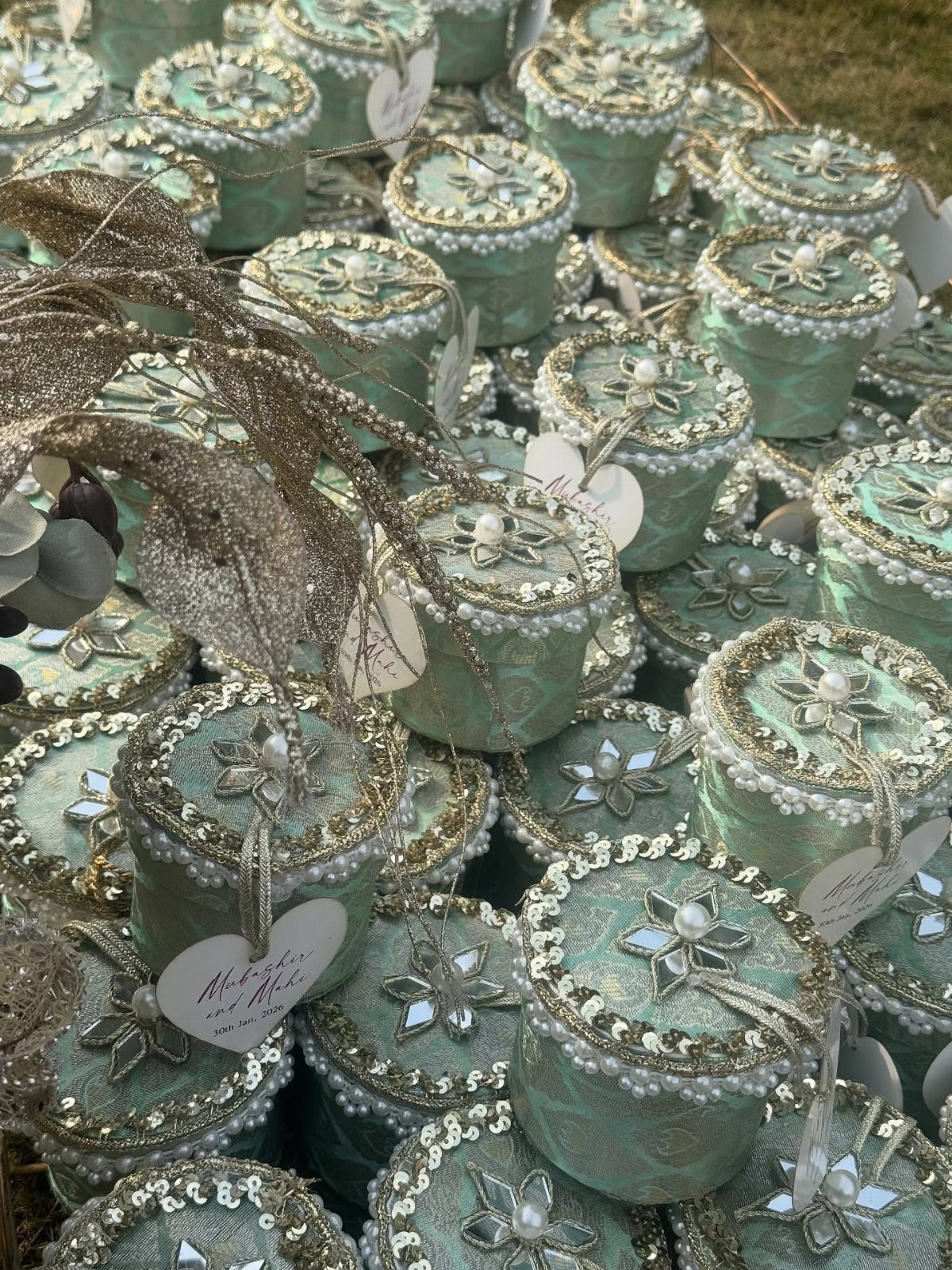 Mint-green ornate gift boxes with pearl details and heart tags arranged together.
