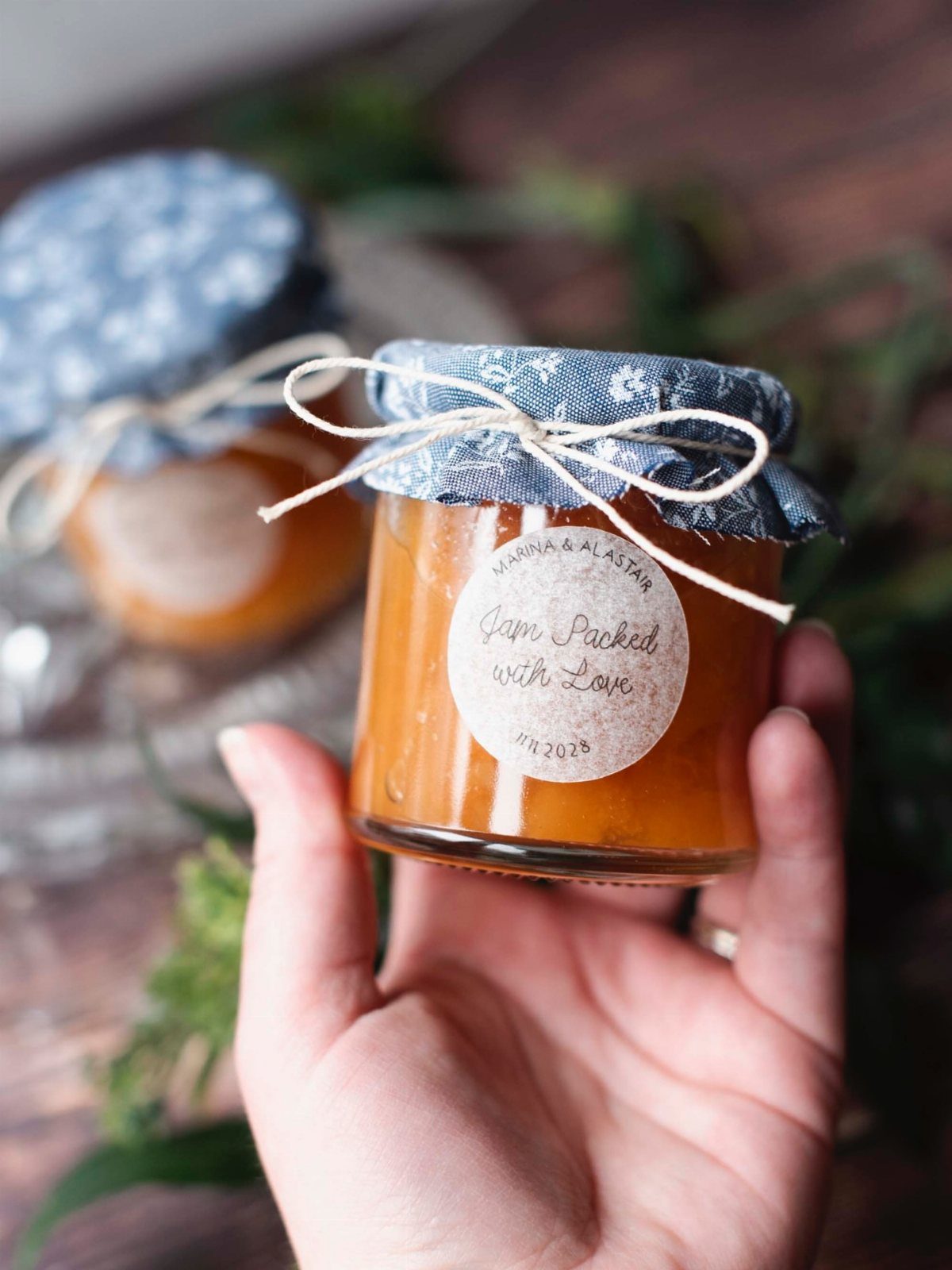 Small glass jar of orange jam with fabric lid and twine bow.