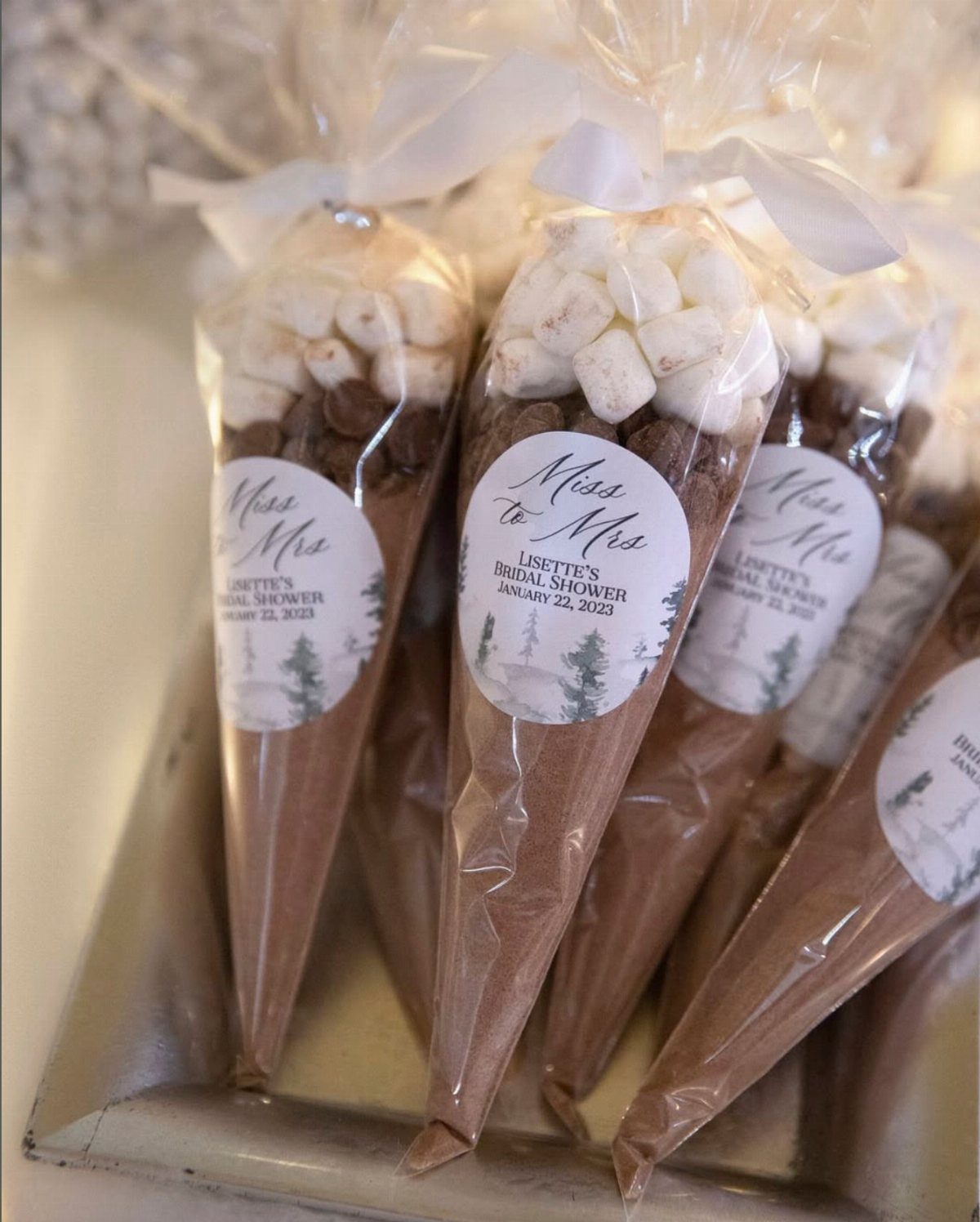 Hot cocoa kits in cone bags with marshmallows and bridal shower labels.
