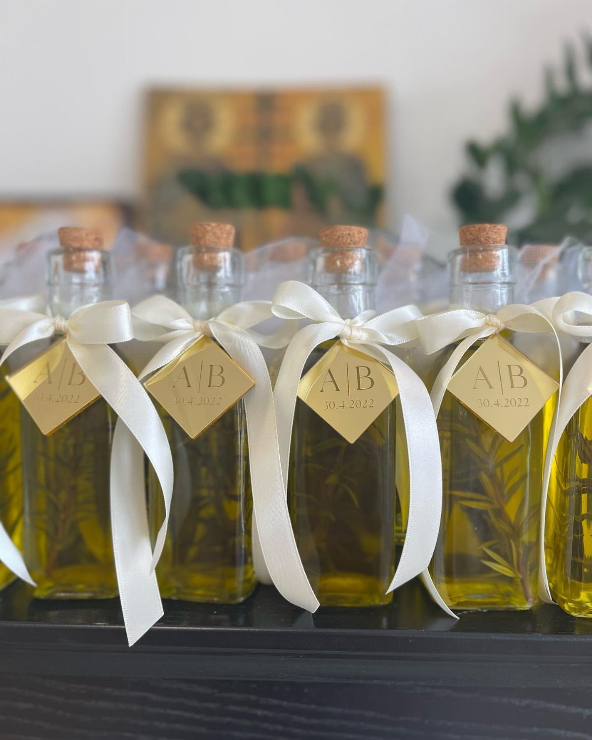 Infused olive oil bottles with rosemary, white ribbons, and gold tags for weddings.