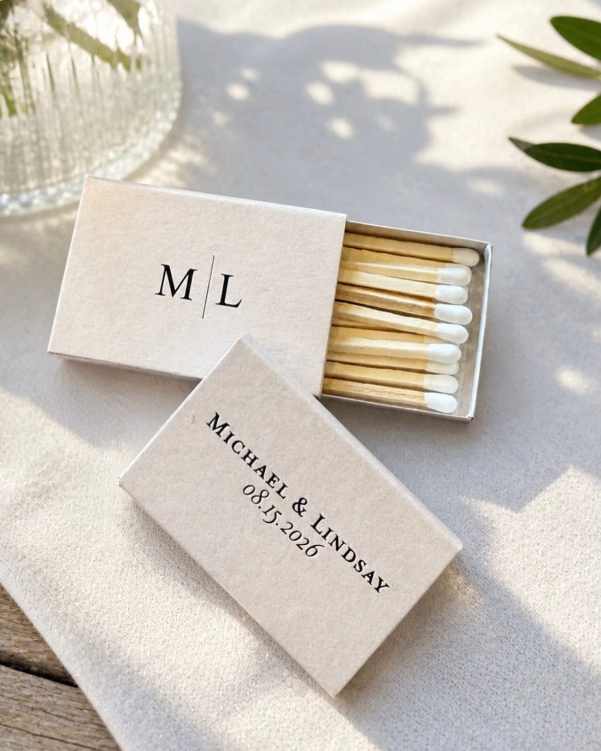 Custom white matchboxes with wedding names and date on a white cloth.
