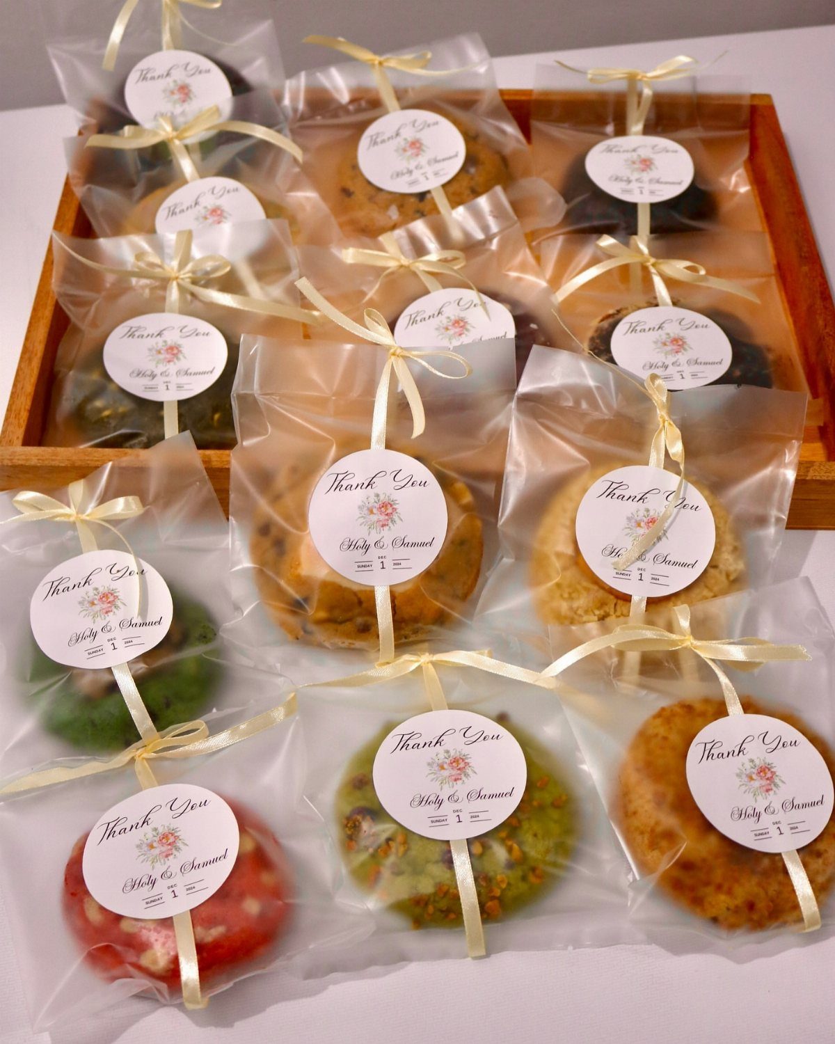 Individually wrapped cookies with thank you labels tied with gold ribbons in a tray