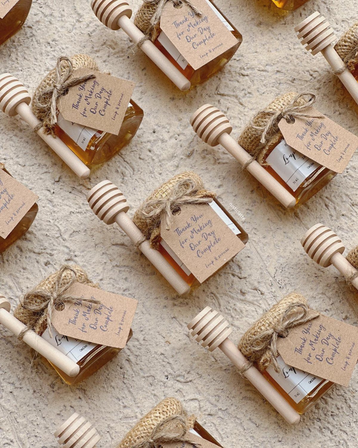 Small honey jars with burlap tops and wooden dippers as wedding favors.