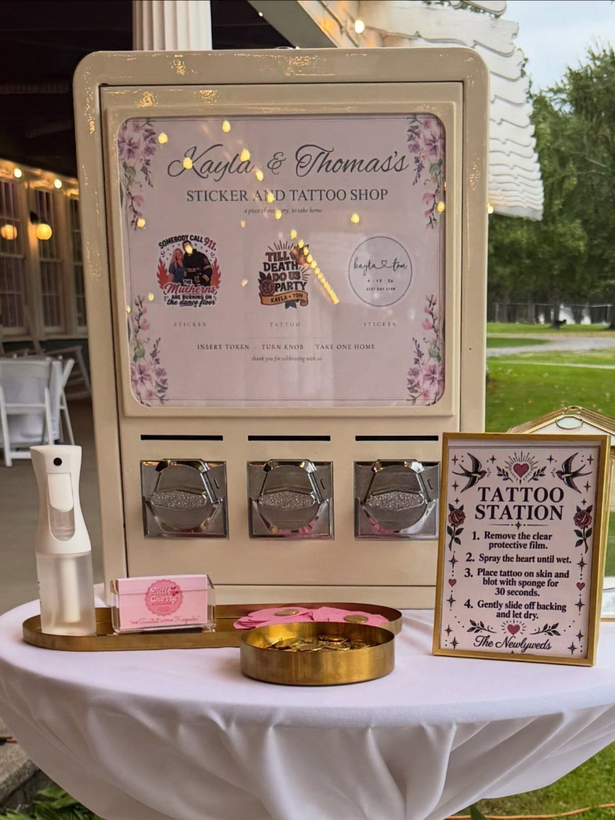 Wedding tattoo station with custom signs, spray bottle, and trays on white table.