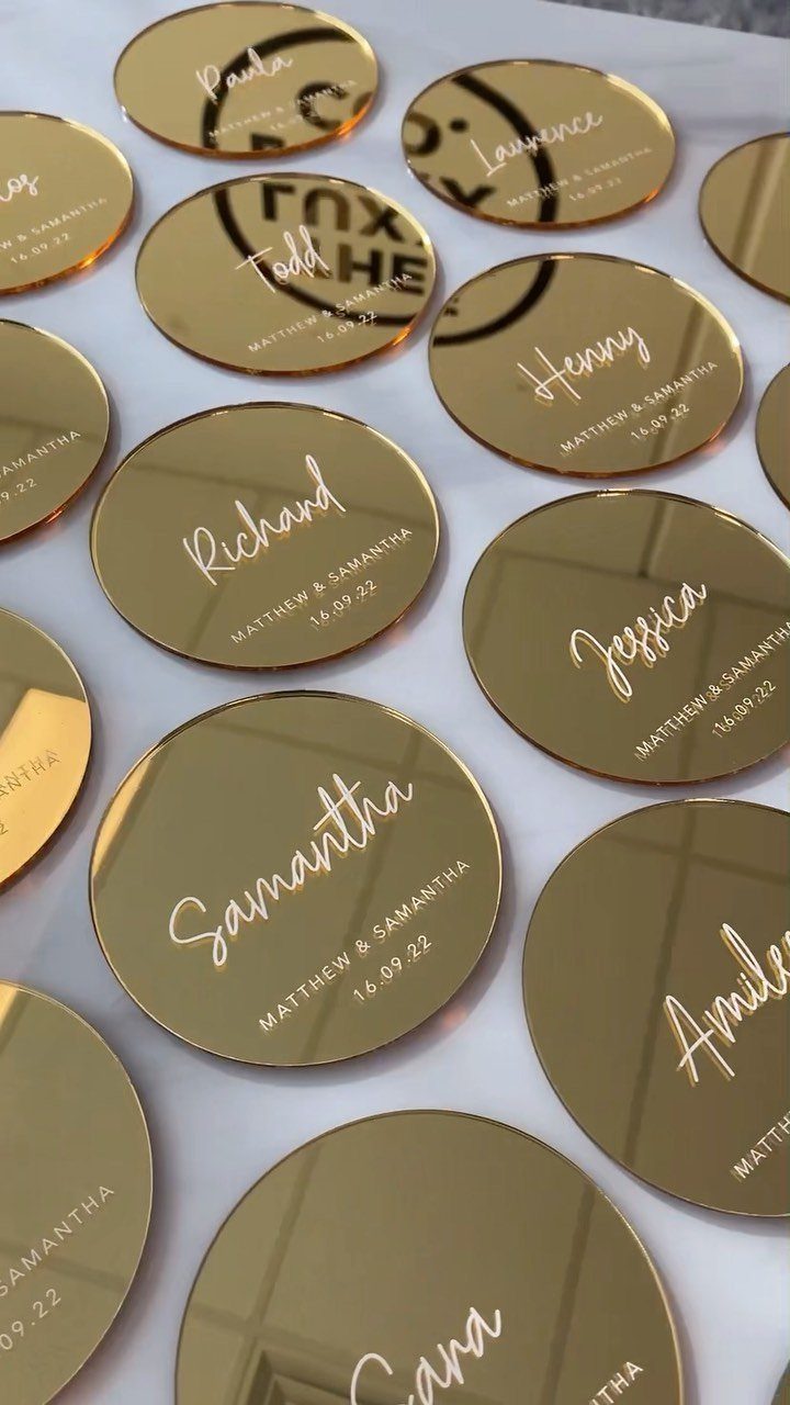 Gold mirrored circular coasters with personalized names and wedding dates in white text.
