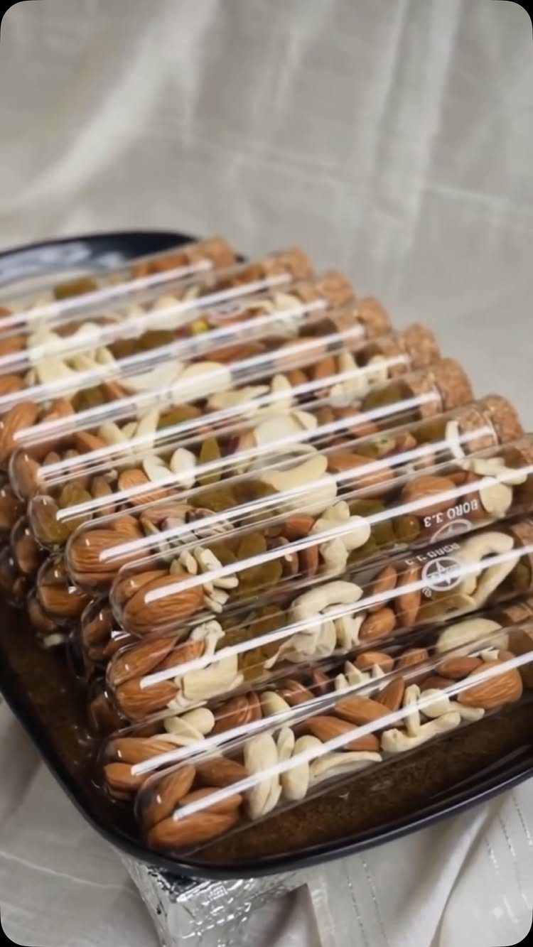Mixed nuts in clear plastic test tubes arranged on a dark serving tray